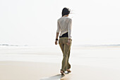 Junge Frau geht am Strand spazieren; Huohu, Taiwan