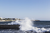 Wellenbrecher auf einem Pier mit Gebäuden entlang der Küste; Paphos, Zypern