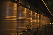 Row Of Spinning Prayer Wheels At Night, One Is Stopped; Kyoto, Japan