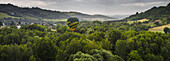 Ein Heißluftballon fliegt tief über die Landschaft eines Frühlingstals; Toskana, Italien