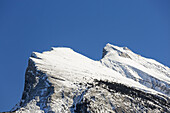 Nahaufnahme eines schneebedeckten Berggipfels und blauer Himmel; Banff, Alberta, Kanada