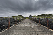 Kaputter, abgenutzter und verwitterter Betonweg unter Gewitterwolken; Argyll und Bute, Schottland