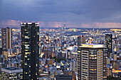 Gewitterwolken über einer mit Lichtern beleuchteten Stadt; Osaka, Japan