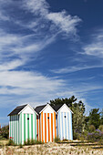 Three Colourful Striped Painted Outhouses On A Sandy Grassy Hill With Trees; Roscoff, Brittany, France