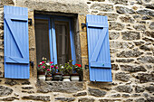 Nahaufnahme von bunt bemalten blauen Fensterläden und Fensterrahmen an einem Steingebäude mit Blumentöpfen auf der Fensterbank; Brest, Bretagne, Frankreich
