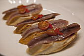 A Dish Of Pintxos In A Bar With Anchovies, Tomatoes And Fish Roe On Bread; San Sebastian, Spain