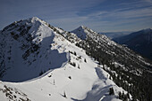 Verschneiter Berghang mit blauem Himmel und Blick auf eine Bergkette; Kicking Horse, British Columbia, Kanada