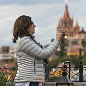 Woman Taking A Photograph With A Smart Phone And A Church In The Distance; San Miguel De Allende, Guanajuato, Mexico