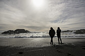 Silhouetten zweier Mädchen, die am Ufer stehen und auf die Wellen schauen, Vancouver Island; Tofino, British Columbia, Kanada