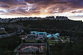 Moderne Gebäude und Tennisplätze unter leuchtenden Wolken bei Sonnenuntergang; Israel