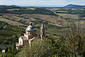 Gebäude mit Kuppel und spitzem Turm und Blick auf Felder in einer Hügellandschaft; Montepulciano, Toskana, Italien