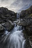 Ein Strom fließt über einen Wasserfall an der Ostküste Islands; Island