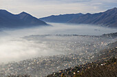 Fog Sets In Over A City And Alpine Lake; Locarno, Ticino, Switzerland