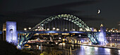 Nachts beleuchtete Tyne-Brücke über den Fluss Tyne mit einer Mondsichel am Himmel; Newcastle, Tyne And Wear, England