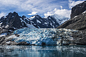 Blue Glacier Between Snow-Capped Mountains And Fjord; Antarctica