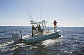 A Man Standing Fishing Off The Edge Of A Boat On The Atlantic Coast; Cape Cod, Massachusetts, United States Of America