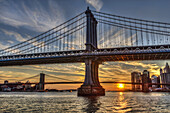 Sun Setting Behind Manhattan And Brooklyn Bridges; New York City, New York, United States Of America
