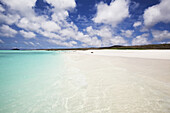Weißer Sandstrand mit kristallklarem türkisfarbenem Wasser und blauem Himmel