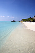 Klassischer weißer Sandstrand mit blauem Meer und Überwasser-Cabana