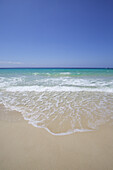 Inselstrand mit weißem Sand, kristallklarem türkisfarbenem Wasser und blauem Himmel