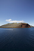 Landschaftsblick vom Meer der Insel Rabida oder Jervis mit Boot im Vordergrund, Galapagos, Ecuador