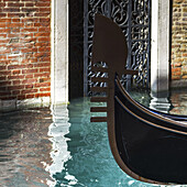 Bug einer Gondel vor einer Tür in einem Kanal mit türkisfarbenem Wasser; Venedig, Italien