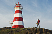 Hiker Looking Out Over Brier Island Lighthouse, Brier Island, Bay Of Fundy; Nova Scotia, Canada