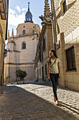 Asiatisches Mädchen geht die Straße entlang mit der Kathedrale von Segovia im Hintergrund; Castilla Leon, Spanien