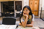 Eine chinesische junge Frau sitzt in einem Restaurant; Spanien