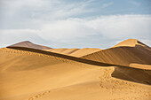 Endlose Sandwellen und menschliche Fußspuren auf einer Sanddüne in der Namib-Wüste; Namibia