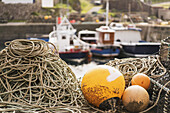 Bojen an Seilen mit vertäuten Fischerbooten im Hintergrund; St. Abbs Head, Scottish Borders, Schottland