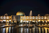 Lichter, die Wasserfontänen und ein Gebäude bei Nacht beleuchten; Isfahan, Iran