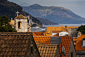 Blick auf Dächer, einen Turm mit einem Kreuz und die Küste; Dubrovnik, Kroatien