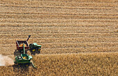 A combine harvester unloads soybeans into a grain wagon on the go during the harvest, near St. Adolphe; Manitoba, Canada