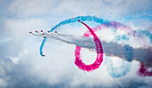 Red Arrows air display, nine planes flying in formation with colourful contrails; South Shields, Tyne and Wear, England