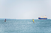 Windsurfer mit einem Schiff in der Ferne; Italien