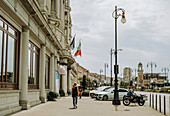 Fußgänger gehen an historischer Architektur entlang einer Straße vorbei; Italien