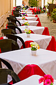 Tische auf einer Außenterrasse in einem Restaurant in Italien, an denen ein männlicher Tourist sitzt und sein Smartphone benutzt; Syrakus, Sizilien, Ortigia, Italien