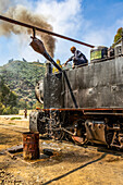 Ingenieur füllt Wasser in die Dampflokomotive Ansaldo 442 aus dem Jahr 1938, die für den Transport von Gütern von der Hafenstadt Massawa in die Hauptstadt Asmara eingesetzt wird; Arbaroba, Zentralprovinz, Eritrea