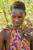 Portrait of young Hadzabe hunter wearing baboon skin cloak and colorful clothing near Lake Eyasi; Tanzania