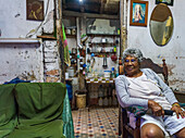 Ältere kubanische Frau sitzt auf einem Stuhl in ihrem Haus; Havanna, Kuba
