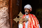 Priester hält ein kunstvolles Prozessionskreuz am Grab Adams in der Nordgruppe der Felsenkirchen; Lalibela, Amhara-Region, Äthiopien