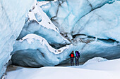 Two winter hikers examine the ice of Black Rapids Glacier; Alaska, United States of America