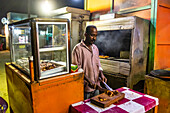 Mann bei der Zubereitung eines Brathähnchens in der Nacht; Karima, Nordstaat, Sudan
