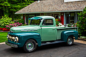 Vor einem Haus mit blühenden Blumen geparkter Oldtimer-LKW; Hudson, Quebec, Kanada