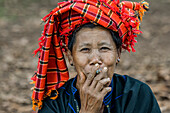 Birmanische Frau mit traditioneller Kopfbedeckung und einer Zigarette; Yawngshwe, Shan-Staat, Myanmar
