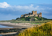 Bamburgh Castle bei Ebbe mit Blick auf die felsige Küste; Bamburgh, Northumberland, England