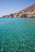 Touristen schwimmen im klaren, türkisfarbenen Wasser der Bucht von Galazia Nera; Insel Polyaigos, Kykladen, Griechenland