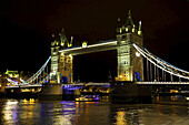 Die Tower Bridge ist nachts beleuchtet und spiegelt sich im ruhigen Wasser der Themse; London, England