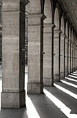 Square columns in a row with shadows cast on the ground; Paris, France
